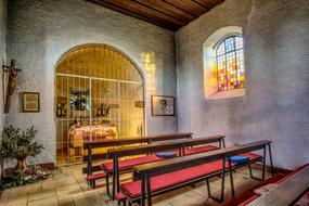 Wooden benches in the beautiful and colorful chapel with stained glass window