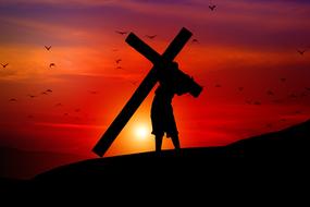 Silhouette of Jesus, with the cross, on the hill, at colorful and beautiful sunset with clouds