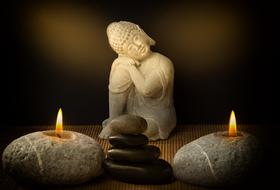 closeup picture of the candlesticks with candles and Buddha figurine and folded pebbles