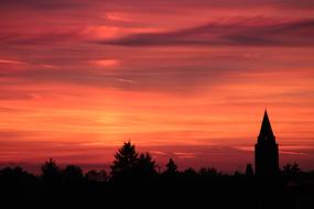 church tower and trees against the backdrop of a bright pink sunset in Hanau