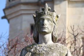 Statue of the king with the crown and background with the building and trees