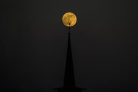 spire of a cathedral in Luxembourg on a background of a full yellow moon