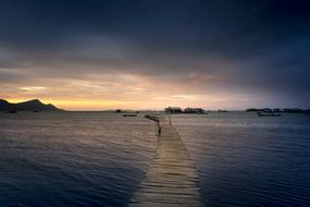 long wooden pier on water at dusk