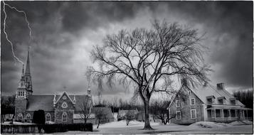 black and white photo of a church against a stormy sky and lightning