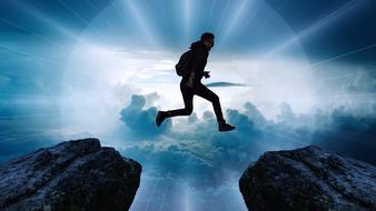 silhouette of a man jumping on the top of the mountain