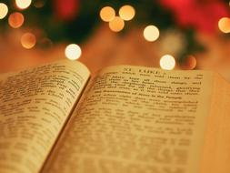 Close-up of the beautiful, open Bible book, at background with colorful bokeh lights on Christmas