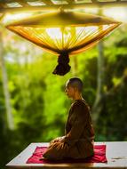 monk meditating under an umbrella