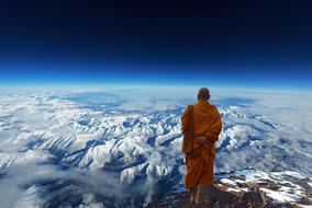 Buddhist Monk stands on rock looking at gorgeous mountains