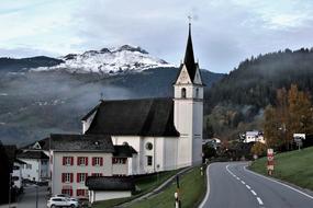 Beautiful landscape of the church, near the highway, and snowy mountains, in the Alpejka Village in Switzerland
