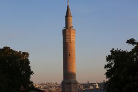 tall brick Minaret in front of city at dusk in turkey, istanbul