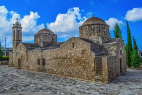 blue sky with white clouds over stone church in cyprus