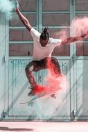 skateboarder, young dark skin man jumps with holi powder