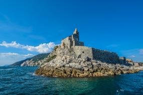 castle on the rocky coast of italy on a sunny day