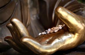 pebbles on Buddha statue hand