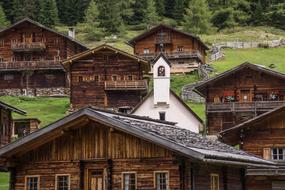 white stone church among old traditional wooden houses in village, austria, tyrol