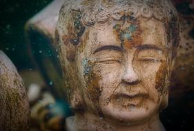 Portrait of the beautiful and colorful sculpture of Buddha, at blurred background
