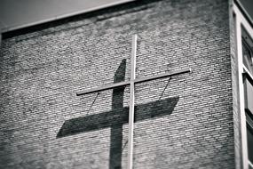 Black and white photo of the cross, with the shadow on the building