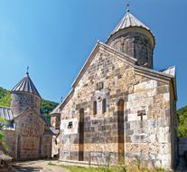 Beautiful and colorful Monastery of Haghartsin, among the green plants, in Armenia, in sunlight, at blue sky on background