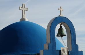 bell in front of blue dome of orthodox Church, greece