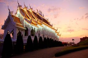 Beautiful, white and gold Wat Huay Pla Kung temple in Chiang Rai, at colorful sunset in the sky, in Thailand