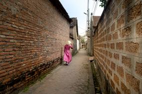 woman is walking down the street in an ancient village in Hanoi