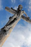 wooden cross with jesus on the background of the sky with clouds