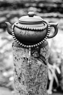 Black and white photo of the beautiful, patterned teapot with praying beads on the pole in India