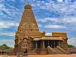 Beautiful Brihadishvara Temple, in Thanjavur, India, among the green trees, at blue sky with white clouds on background