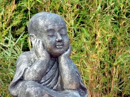 statue of a buddhist monk on a background of green bamboo