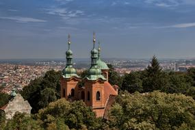 towers of Baptist Cathedral of st lawrence at panoramic view among green plants of city, Czech, Prague
