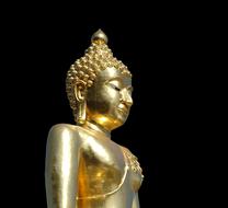 Beautiful, shiny, gold statue of Buddha in Thailand, at black background