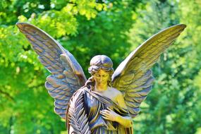 Beautiful and colorful stone sculpture of the angel, near the colorful and beautiful plants, in light