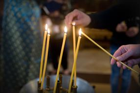 People lighting beautiful, burning candles in the Christian church