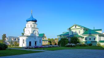Beautiful church with blue dome among the buildings and trees at blue sky