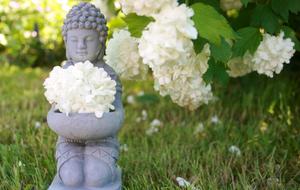 kneeling Buddha, garden sculpture with hydrangea flowers