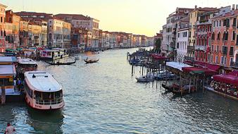 tourist boats at pier and gondolas on channel at evening, Italy, Venice
