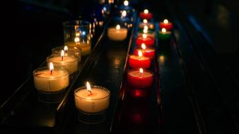 Beautiful, burning, yellow and red candles, among the darkness, in the church