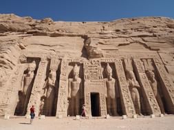 Person near the beautiful Abu Simbel Temple with statues, at blue sky on background in Egypt