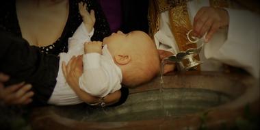 baby on hands of mother above Baptismal Font in Church