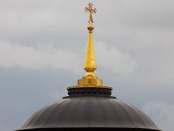 golden Cross on spire at top of Dome Of The Cathedral at cloudy sky