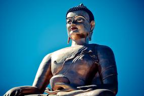 a large statue of Buddha against a blue sky in Bhutan