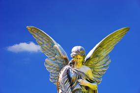 Beautiful and colorful stone sculpture of the Angel, at blue sky with white clouds on background