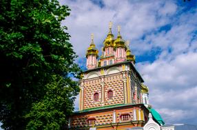 cathedral with golden domes behind green trees