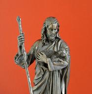 metal sculpture of Jesus on an orange background