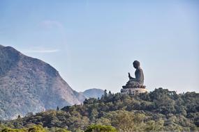 Beautiful statue of Buddha on the Lantau, among the colorful plants in Hong Kong, among the mountains