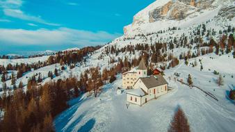 Beautiful landscape with the church, among the colorful trees, on the snowy mountain in Alta Badia, Italy