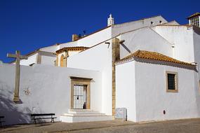 Beautiful white church with the cross at blue sky on background, in Faro, Algarve, Portugal