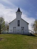 Old white church on the green hill among the plants
