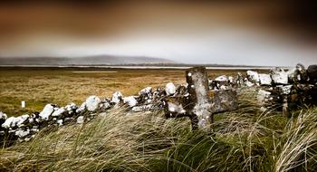 old stone cross at scenic rural landscape, ireland