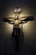 wooden cross with a crucifix on the wall in the light